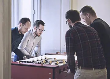 Four Salsita team members playing foosball in the office