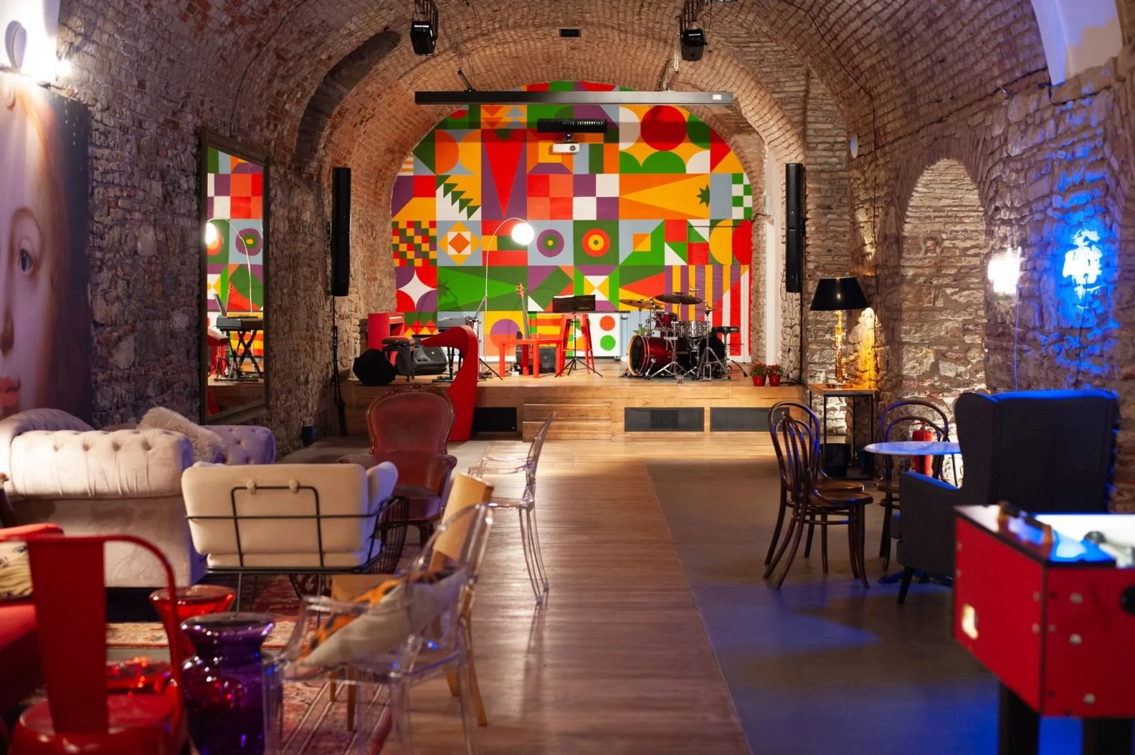 Interior of the Salsita Club with a colorful geometric stage mural, musical instruments and lounge seating