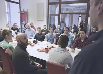 Salsita employees seated around a long conference table listening to a colleague give a talk