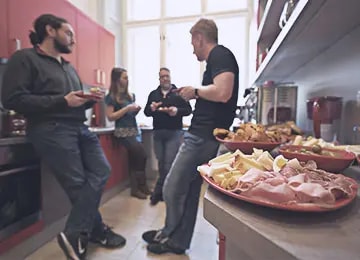 Group of Salsita employees gathered around food in the office kitchen during a team event