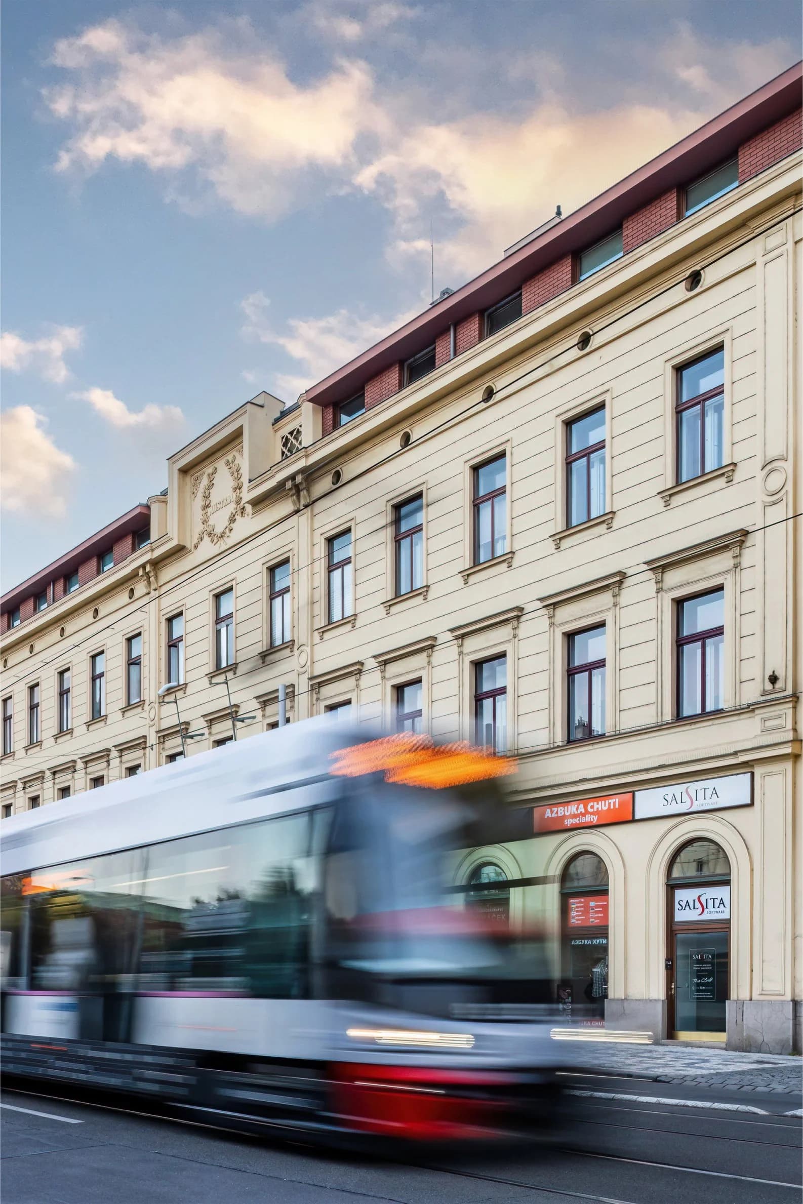 The Salsita office street in Prague with a red tram passing by